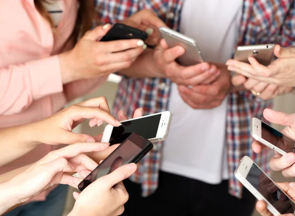 Many hands holding mobile phones close up