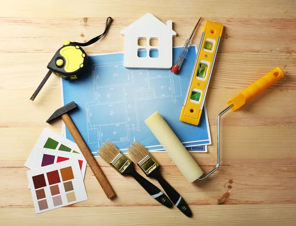 Construction instruments, plan, color samples and brushes on wooden table background