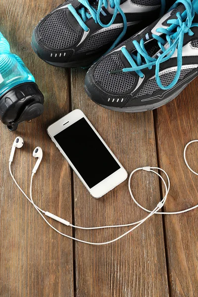 Sneakers and earphones on wooden table, top view