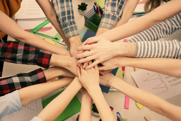 United hands of business team on workspace background top view