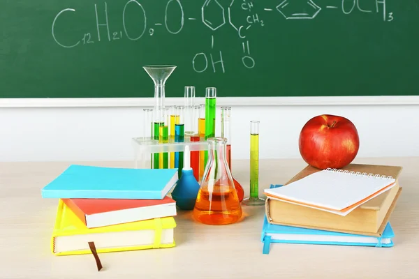Desk in chemistry class with test tubes on green blackboard background