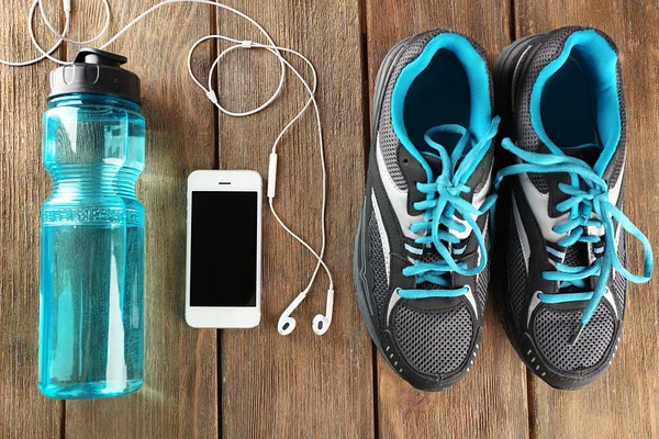 Sneakers and earphones on wooden table, top view