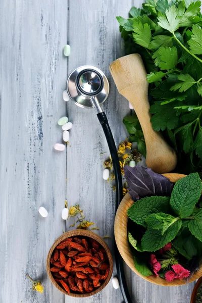 Alternative medicine herbs, berries and stethoscope on wooden table background