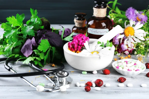 Alternative medicine herbs, berries and stethoscope on wooden table background