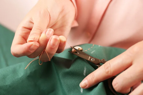 Closeup hands of seamstress at work with cloth fabric