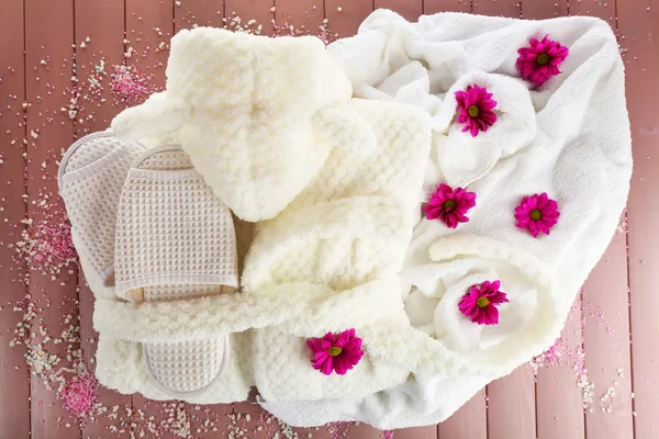 Bathrobe, towel and slippers on wooden surface, top view