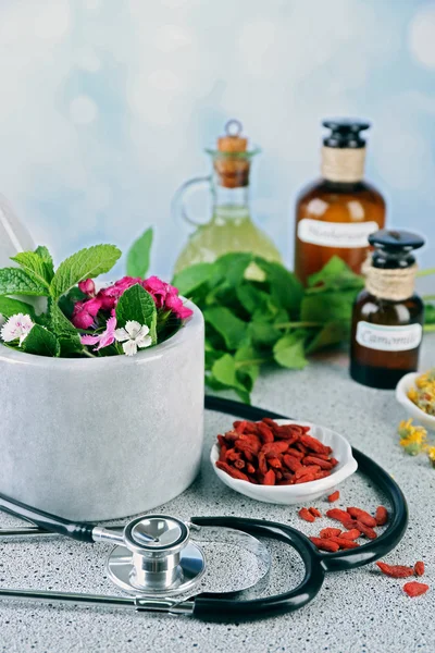 Alternative medicine herbs and stethoscope on wooden table, on light background