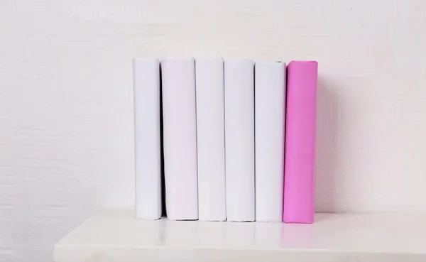 Blank books and pink one on shelf