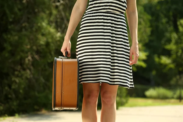 Young woman holding vintage suitcase outdoors