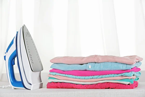 Electronic ironing and pile of clothes