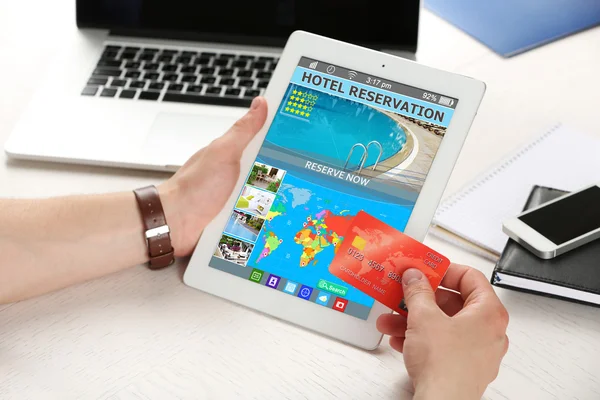 Man holding tablet with screen interface of booking hotels