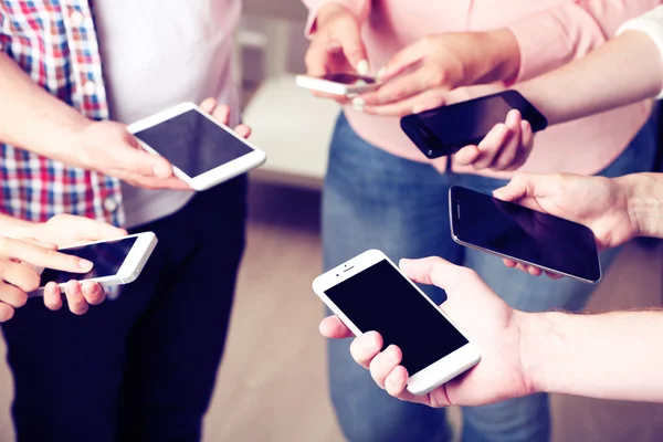 Many hands holding mobile phones