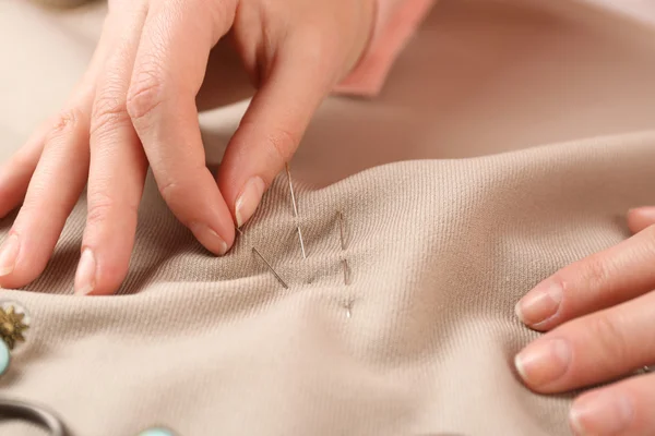 Closeup hands of seamstress at work with cloth fabric