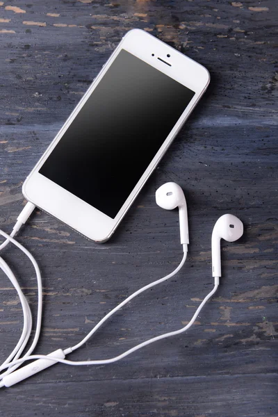 Mobile phone and earphones on wooden background