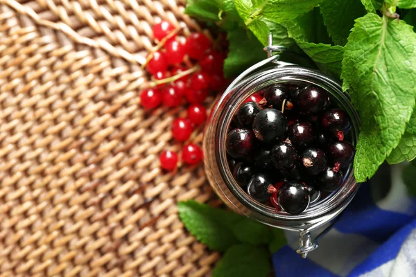 Ripe forest berries in glass jar  on wooden background