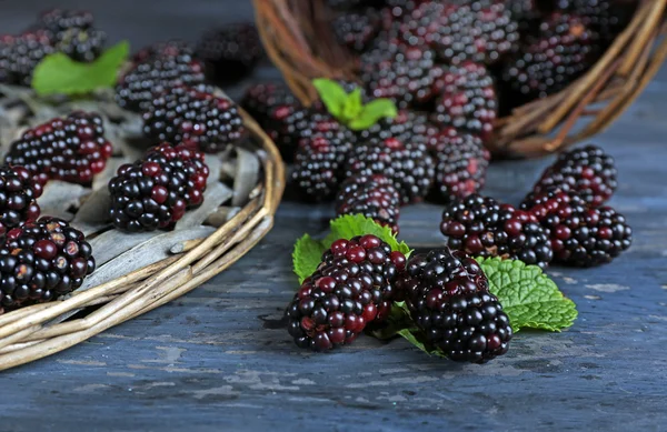 Heap of sweet blackberries with mint in basket