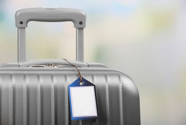 Suitcase with TRAVEL INSURANCE label on light blurred background