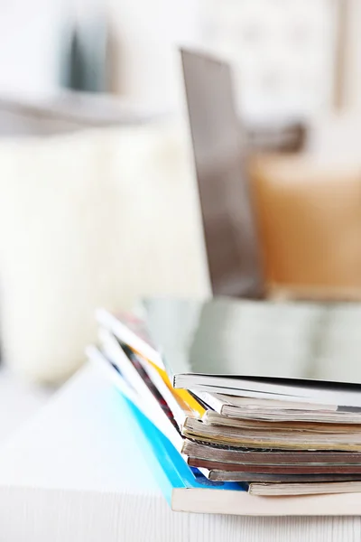 Magazines and laptop on table