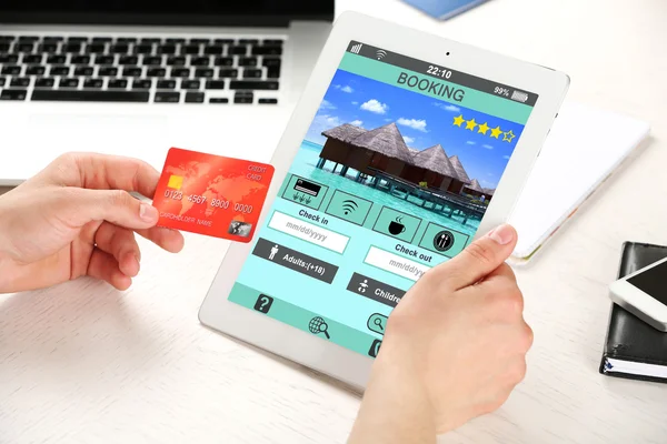 Man holding tablet with screen interface of booking hotels