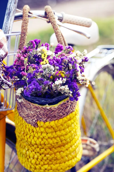 Bicycle with basket of flowers in meadow during sunset