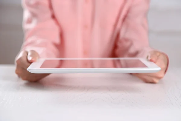Woman holding digital tablet on table close up