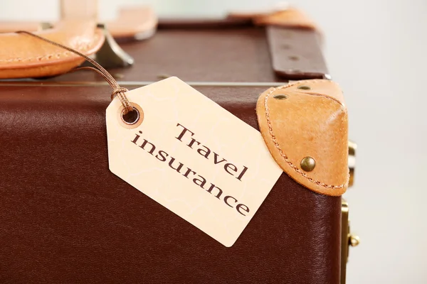 Suitcase with TRAVEL INSURANCE label, closeup