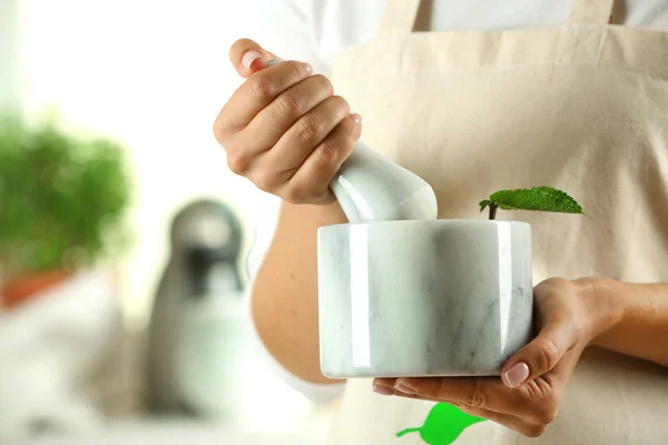 Cook hands with mortar with herbs