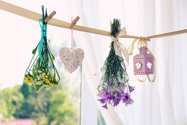 Various herbs, flowers and decorations hanging on thong on light background