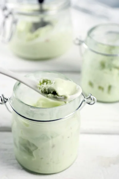 Homemade mint ice-cream in glass jars on light wooden background