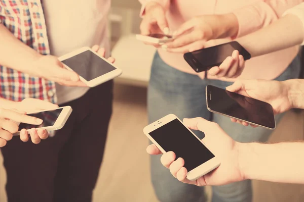 Many hands holding mobile phones close up