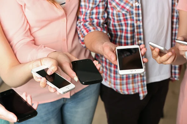 Many hands holding mobile phones close up