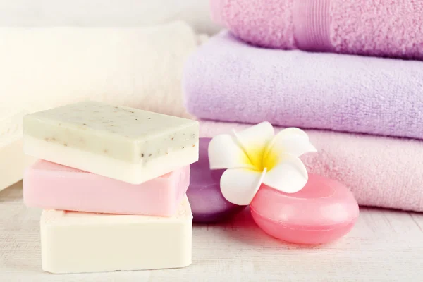 Bars of natural soap and colorful towels on light background