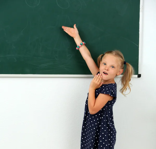 Little girl pointing at something at chalkboard