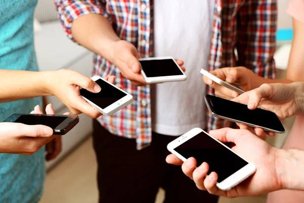 Many hands holding mobile phones