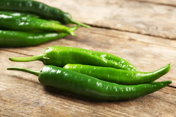 Green hot peppers on wooden table close up