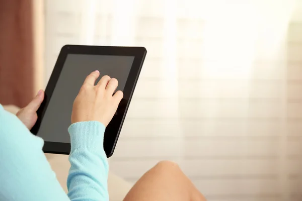 Female hand holding PC tablet on home interior background