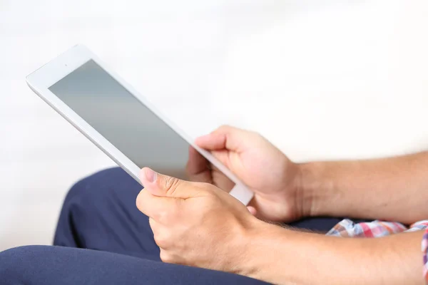 Male hand holding PC tablet on home interior background