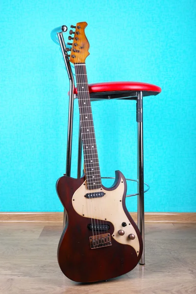 Electric guitar near chair on blue wallpaper background