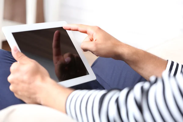 Male hand holding PC tablet on home interior background