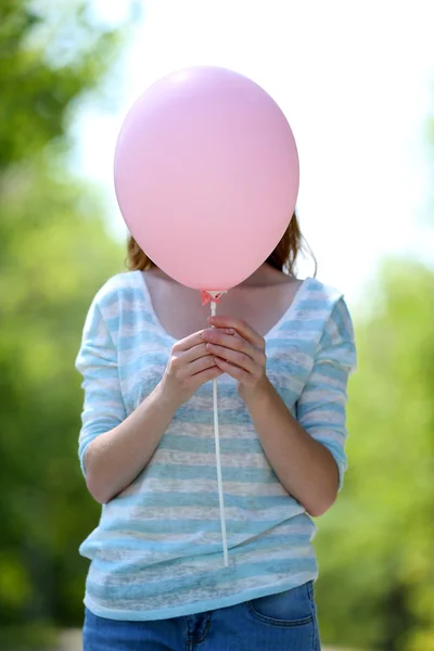 Girl holding balloon near face