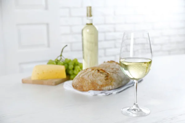 Still life of wine, grape, cheese and bread on light background