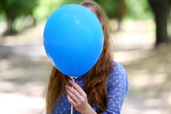 Girl holding balloon near face