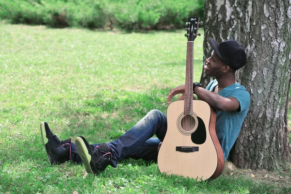 Man with guitar sitting in park