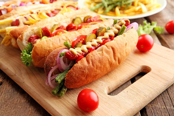 Fresh hot dogs on cutting board and food on plate closeup