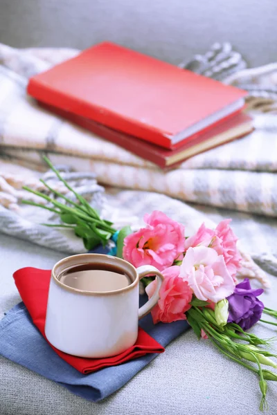 Cup of coffee with flowers near books