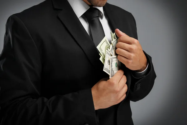 Elegant man in suit holding money on gray  background
