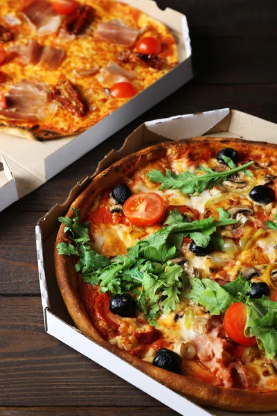 Pizza in box on wooden table closeup