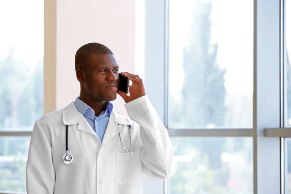 Handsome African American doctor talking on mobile phone in hospital