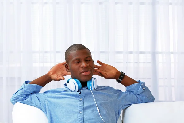 Handsome African American man with headphones lying on sofa close up