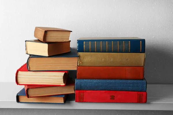 Old books on shelf, close-up, on light wall background